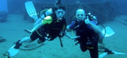 Two adult divers in front of C-53 shipwreck in Cozumel.