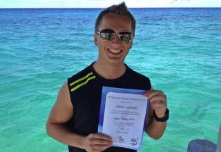 Student diver proudly showing his certificate of completion at the shore