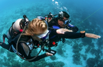 Two divers side by side navigating underwater using a compass and timer