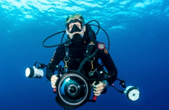 Diver hovering while holding an underwater camera 